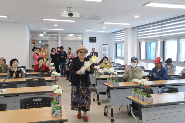 대한노인회 해남군지회 경로대학 어르신들이 조명 카네이션을 만들어 꽃길을 걸으며 춤을 추고 있다. 