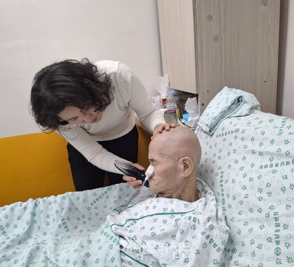 행복한 주간보호센터 김현경 대표가 환자의 머리와 수염을 손질하고 있다.(사진제공 이혜영씨)